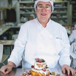 Ana presenting a cake in a cooking class.