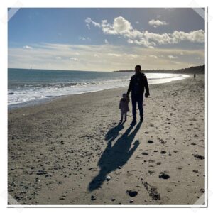 Man and Child walking on a beach in Ireland.