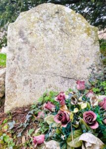 Withered gravestone with flowers, Kilquade, Co. Wicklow, Ireland.